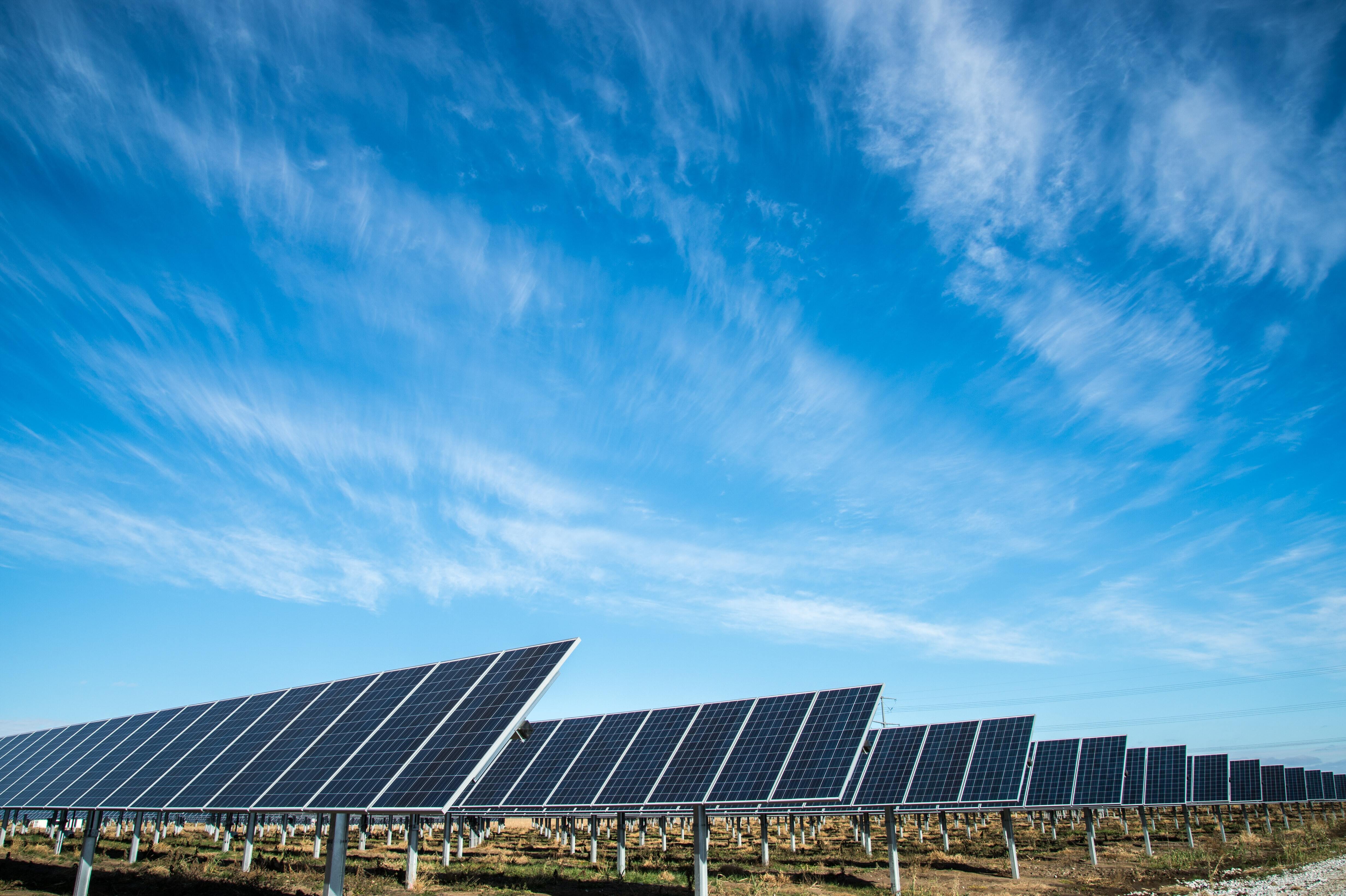 Solar farm with rows of solar panels under a blue sky